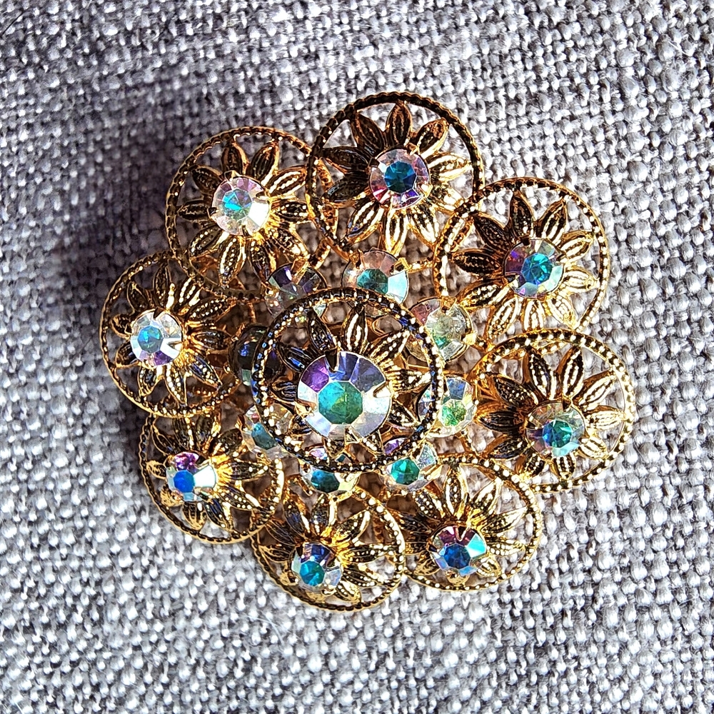 Vintage aurora borealis rhinestone gold-tone filigree floral brooch. 1960's